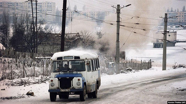 Автобус їде дорогою у Чечні на тлі обстрілів у Грозному, 24 січня 1995 року